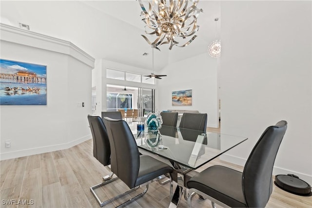 dining room with ceiling fan with notable chandelier and light wood-type flooring