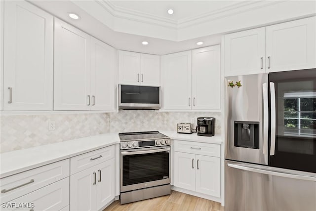 kitchen featuring tasteful backsplash, light wood-type flooring, ornamental molding, stainless steel appliances, and white cabinets