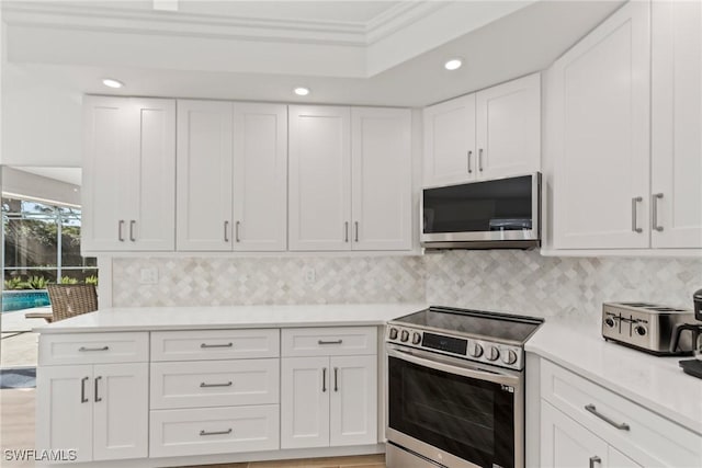 kitchen with white cabinetry, ornamental molding, decorative backsplash, and stainless steel range with electric stovetop