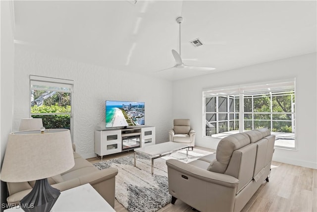 living room featuring plenty of natural light, ceiling fan, and light wood-type flooring