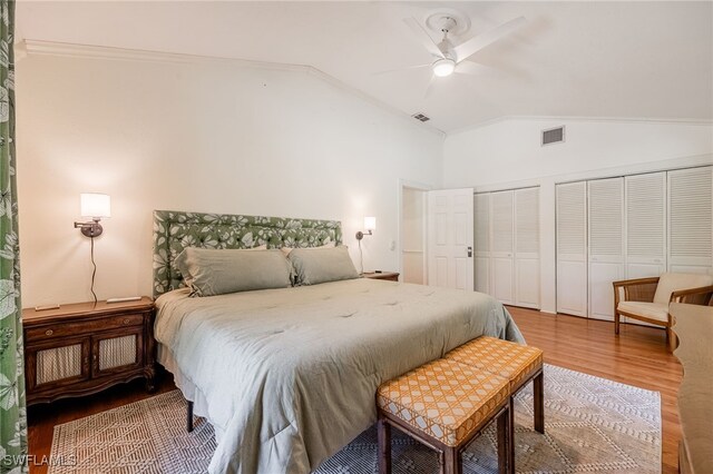 bedroom featuring crown molding, wood-type flooring, vaulted ceiling, multiple closets, and ceiling fan