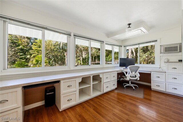 unfurnished office with a wall mounted air conditioner, wood-type flooring, and built in desk