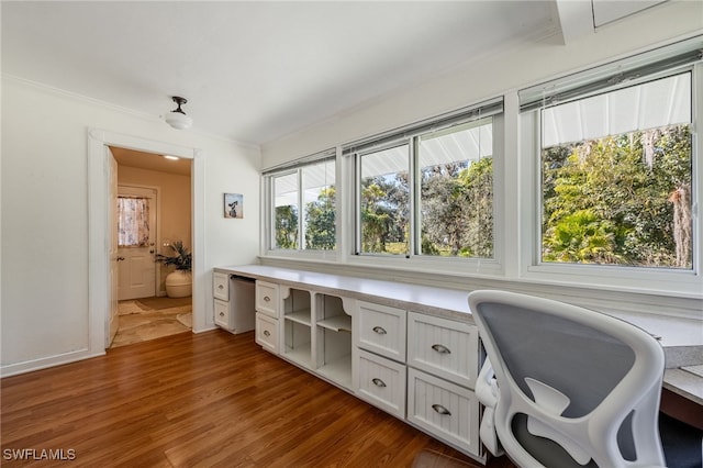 office space featuring ornamental molding, built in desk, and dark hardwood / wood-style flooring