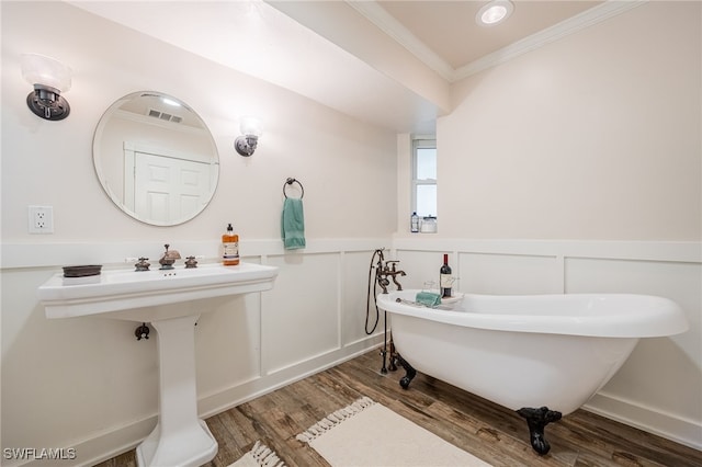 bathroom with hardwood / wood-style flooring, ornamental molding, and a tub