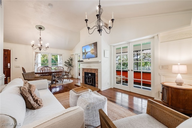 living room featuring a fireplace, wood-type flooring, lofted ceiling, an inviting chandelier, and french doors