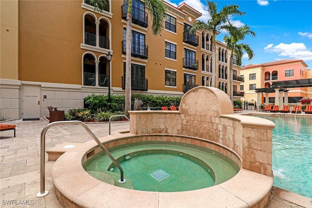 view of pool with a hot tub, a pergola, and a patio area