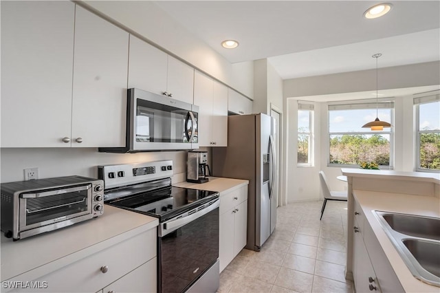 kitchen featuring light tile patterned floors, sink, hanging light fixtures, stainless steel appliances, and white cabinets