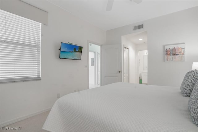 carpeted bedroom with ensuite bathroom and ceiling fan