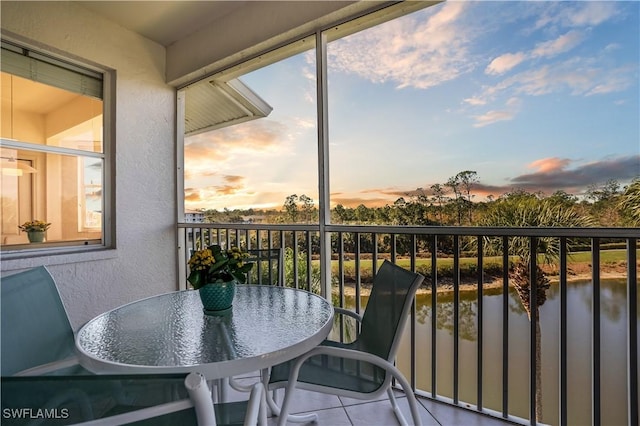 balcony at dusk featuring a water view