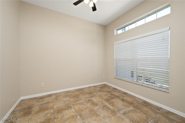 empty room featuring baseboards, a ceiling fan, and stone finish floor