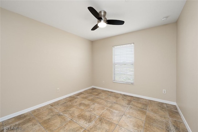 spare room with stone finish floor, baseboards, and a ceiling fan