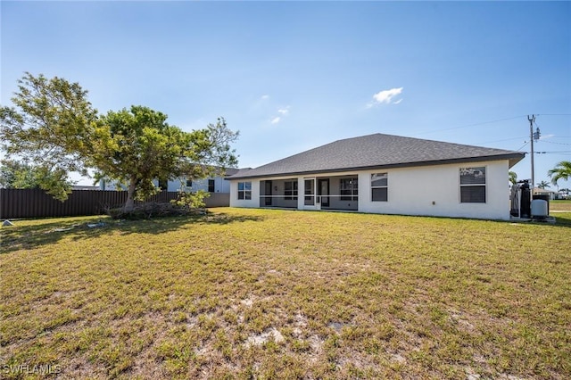 rear view of property with roof with shingles, fence, a lawn, and stucco siding