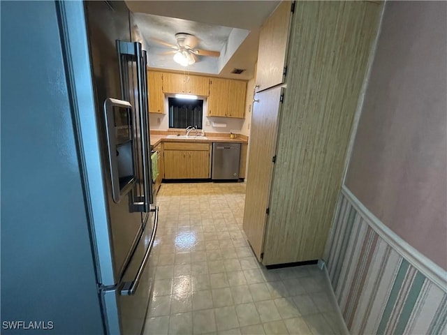 kitchen with appliances with stainless steel finishes, sink, light brown cabinetry, and ceiling fan