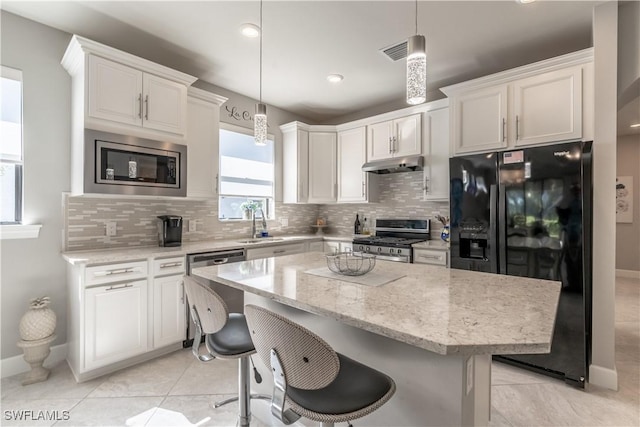 kitchen with appliances with stainless steel finishes, a center island, white cabinets, and decorative light fixtures