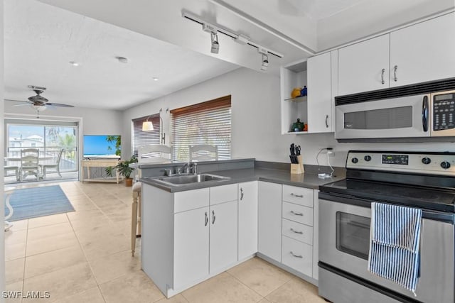 kitchen featuring sink, appliances with stainless steel finishes, white cabinetry, track lighting, and kitchen peninsula