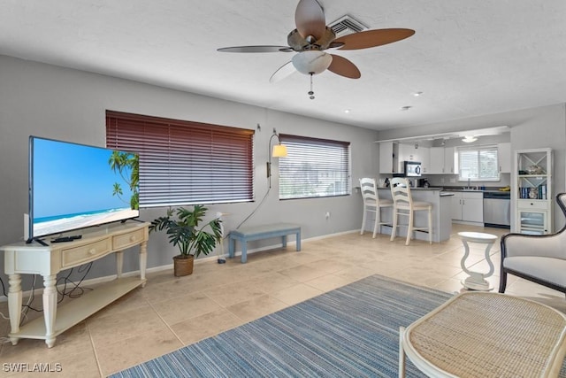 living room featuring sink, light tile patterned floors, and ceiling fan