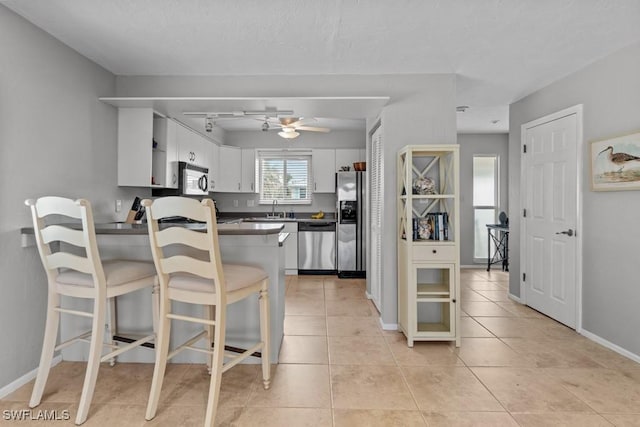 kitchen featuring sink, kitchen peninsula, ceiling fan, stainless steel appliances, and white cabinets