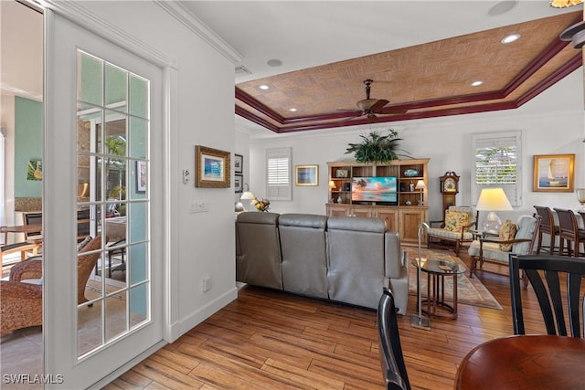 living room featuring crown molding, wood ceiling, ceiling fan, a tray ceiling, and light wood-type flooring