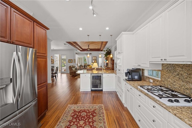 kitchen featuring pendant lighting, white appliances, white cabinetry, kitchen peninsula, and beverage cooler