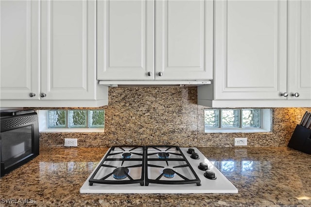 kitchen with tasteful backsplash, white cabinetry, dark stone countertops, and white gas cooktop