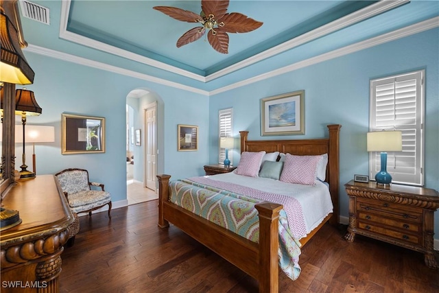 bedroom featuring a raised ceiling, ornamental molding, dark wood-type flooring, and ceiling fan