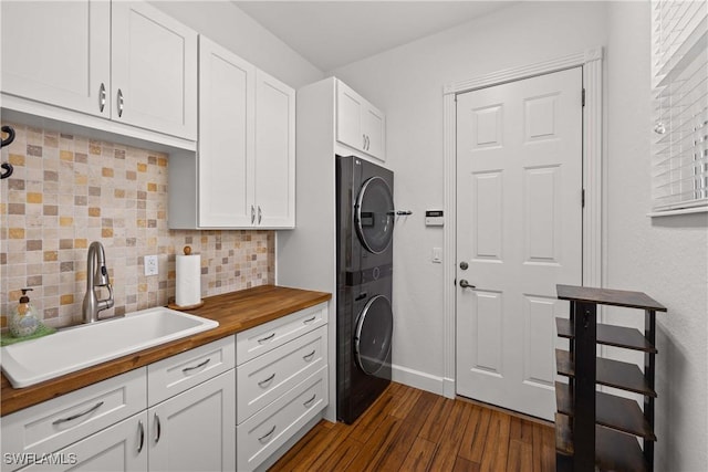 laundry room featuring dark wood-type flooring, cabinets, stacked washer and clothes dryer, and sink