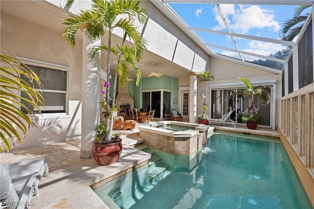 view of pool featuring an outdoor fireplace, a patio, an in ground hot tub, a lanai, and ceiling fan