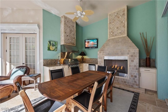 dining room featuring lofted ceiling, sink, ceiling fan, a fireplace, and french doors