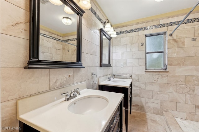 full bath featuring tasteful backsplash, tile walls, two vanities, and a sink