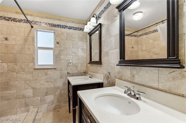 bathroom with curtained shower, two vanities, a sink, and tile walls