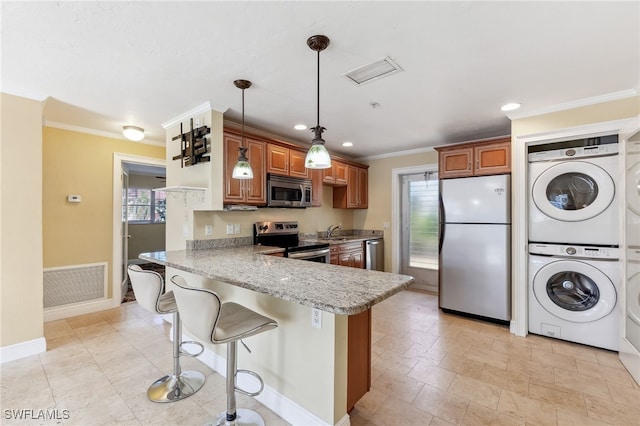 kitchen featuring stacked washer and dryer, visible vents, appliances with stainless steel finishes, and brown cabinetry