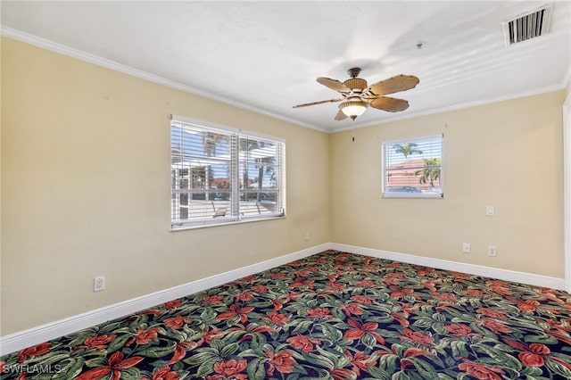 carpeted spare room featuring baseboards, visible vents, and crown molding