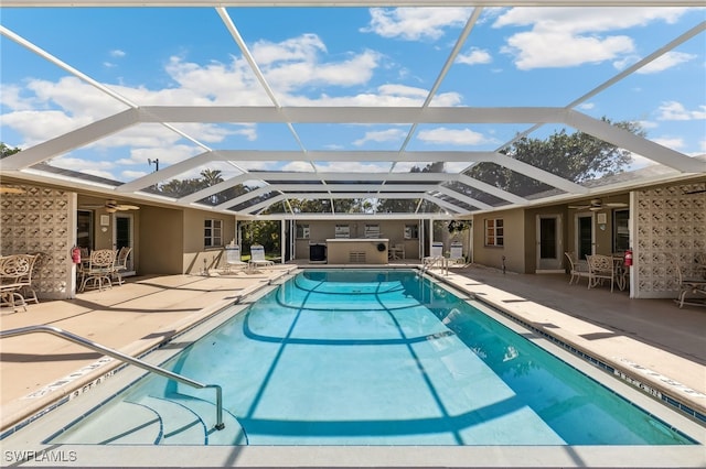 pool featuring a ceiling fan, glass enclosure, and a patio