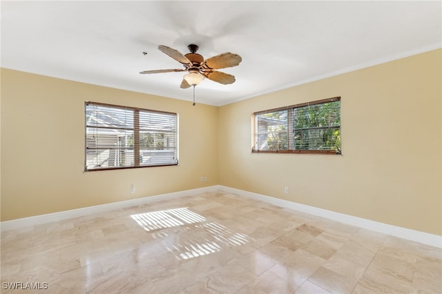 empty room featuring a ceiling fan, ornamental molding, and baseboards