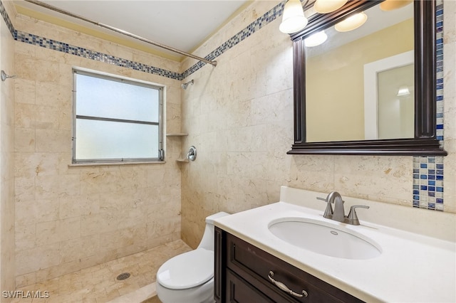 full bathroom featuring toilet, a tile shower, vanity, and tile walls