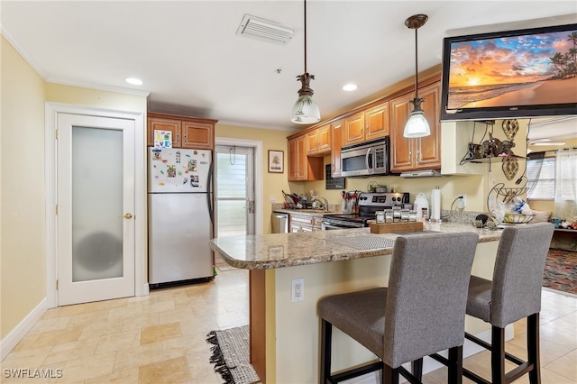 kitchen featuring a breakfast bar area, stainless steel appliances, a peninsula, visible vents, and ornamental molding