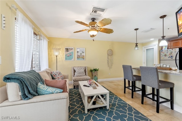 living room featuring baseboards, visible vents, ceiling fan, and crown molding