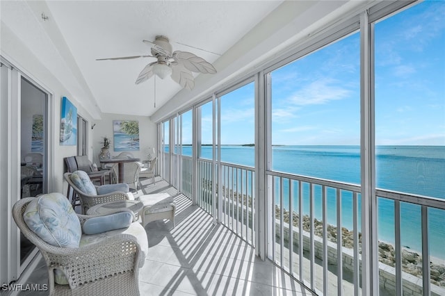 sunroom / solarium featuring a view of the beach, ceiling fan, and a water view