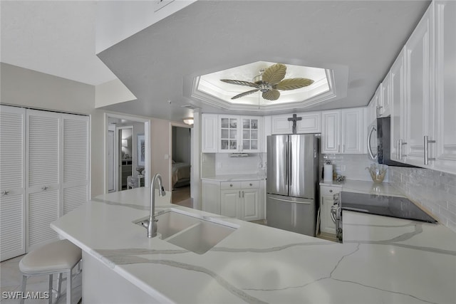 kitchen with tasteful backsplash, sink, white cabinets, and appliances with stainless steel finishes