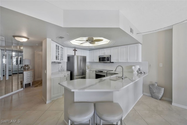 kitchen with a breakfast bar, sink, appliances with stainless steel finishes, kitchen peninsula, and white cabinets