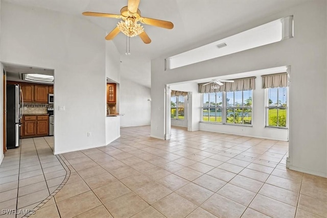 unfurnished living room featuring light tile patterned floors, ceiling fan, high vaulted ceiling, and baseboards