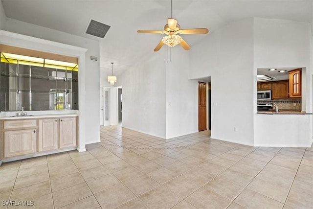 unfurnished living room with ceiling fan, high vaulted ceiling, sink, and light tile patterned floors