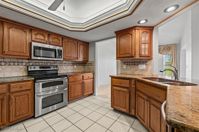 kitchen with sink, crown molding, light tile patterned floors, stainless steel appliances, and a raised ceiling