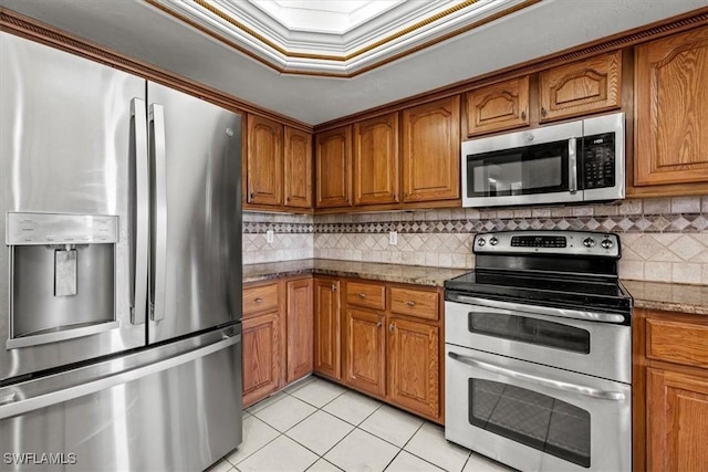 kitchen featuring light stone counters, crown molding, stainless steel appliances, and light tile patterned flooring