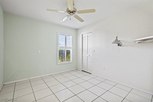 spare room featuring a ceiling fan, light tile patterned flooring, and baseboards