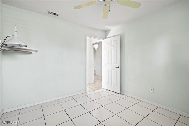 empty room featuring light tile patterned floors, baseboards, visible vents, and a ceiling fan