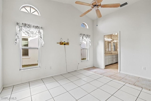 empty room featuring visible vents, a ceiling fan, light tile patterned flooring, high vaulted ceiling, and baseboards