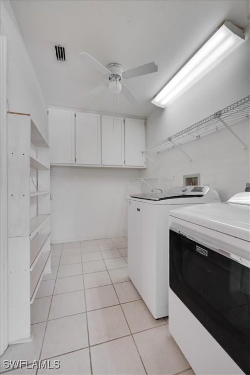 washroom featuring cabinets, light tile patterned flooring, washer and dryer, and ceiling fan