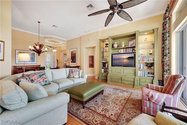 living room with light wood-style flooring, ceiling fan with notable chandelier, visible vents, and ornamental molding