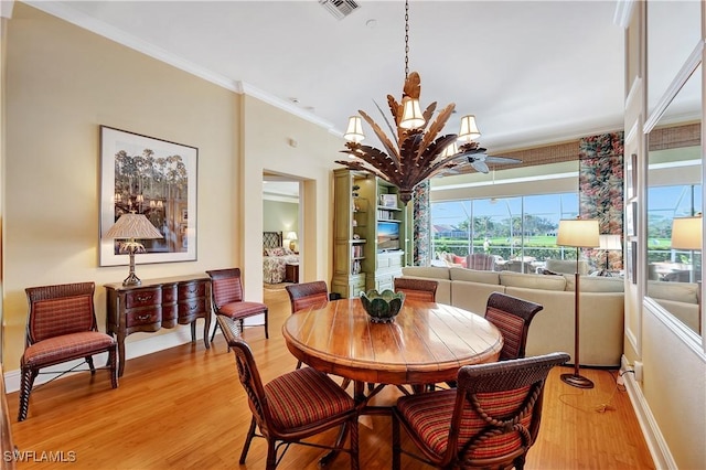 dining area featuring baseboards, visible vents, wood finished floors, crown molding, and a chandelier